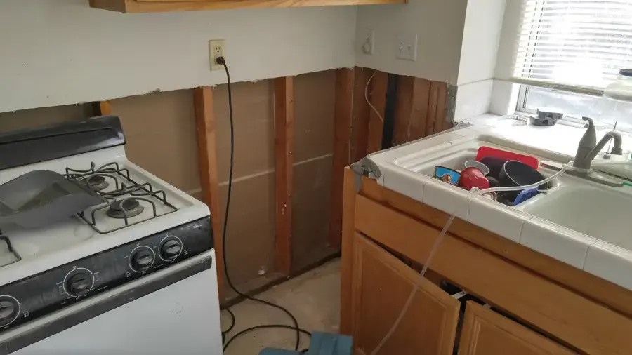 Kitchen walls cut open below the counters so the cavities can dry in a Hayward home